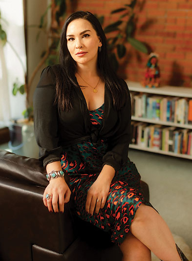 woman sitting on a leather chair in a room with bookshelf in the background