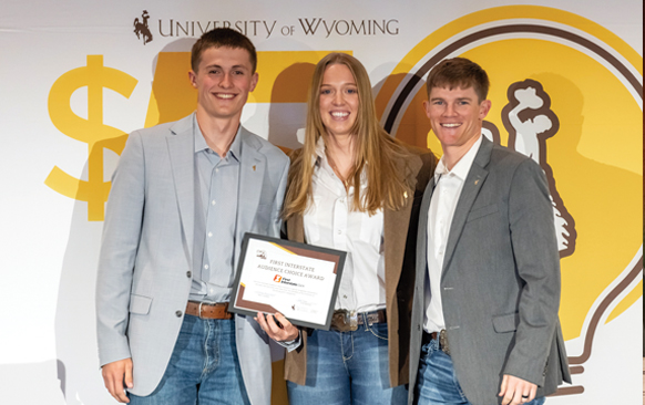 two men and one woman stand together holding a certificate