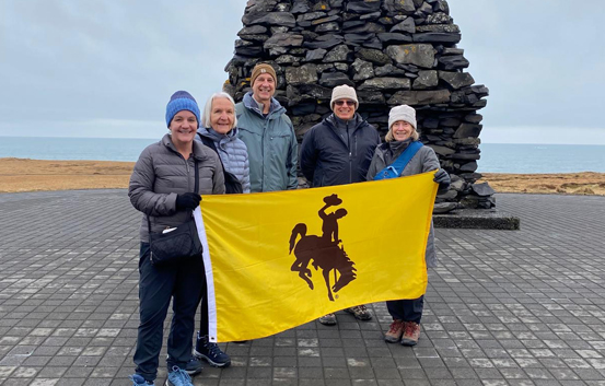 group of adults holding a UW flag in Iceland