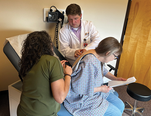 two health care works and a patient in a doctors office