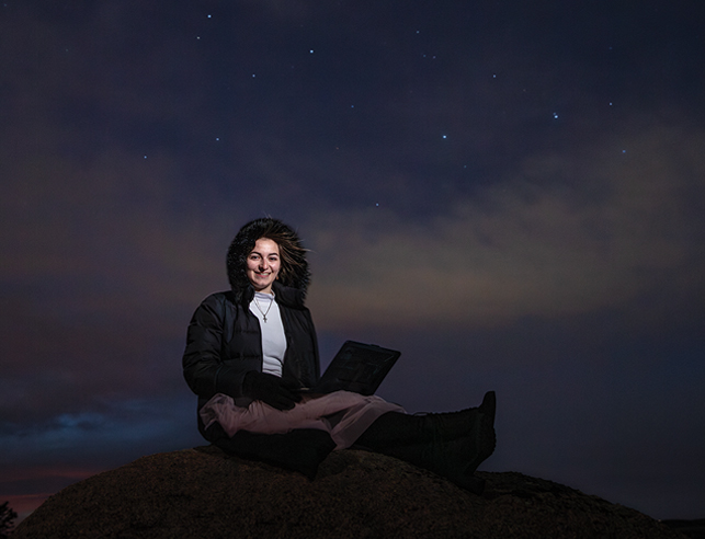 woman sitting with a laptop at night outside