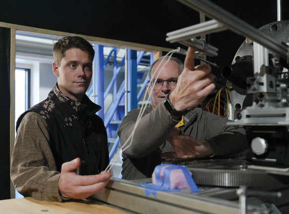 Male student and professor work with lab equipment