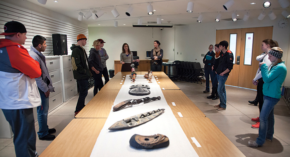 group of students look at art pieces on a table