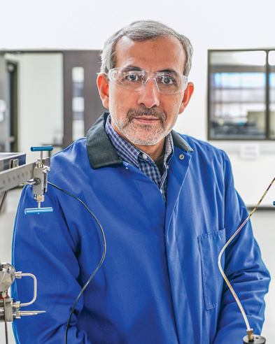 man in a blue labcoat by equipment