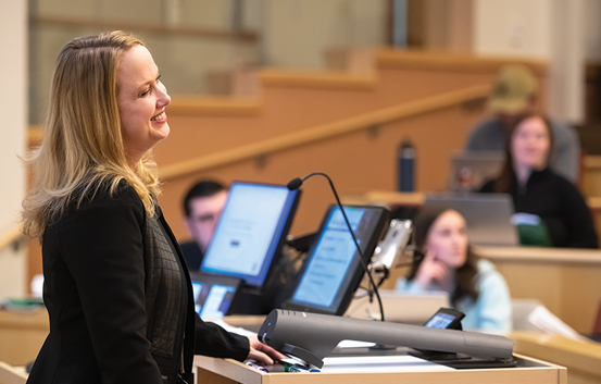 female professor at a podium lecturing students