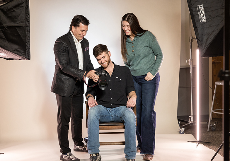 three people at a photo shoot looking at a camera