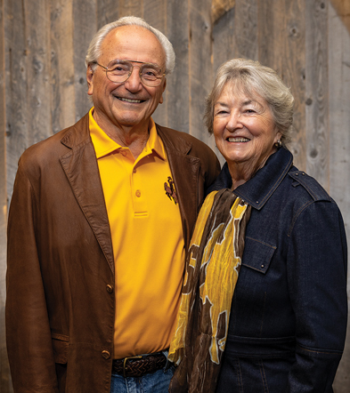 older man and woman pose in UW gear