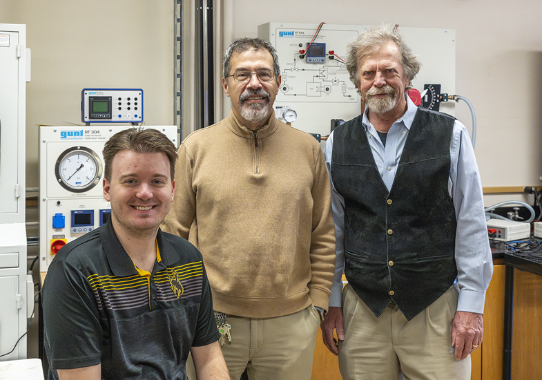 Three men in a room with science equipment