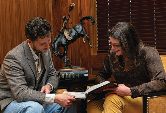 Female professor looks at a book with a male student