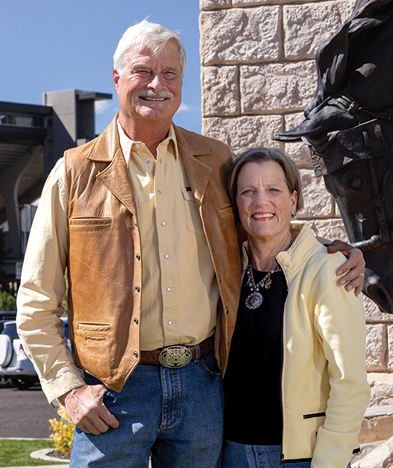 man and woman pose in front of Breaking Through statue