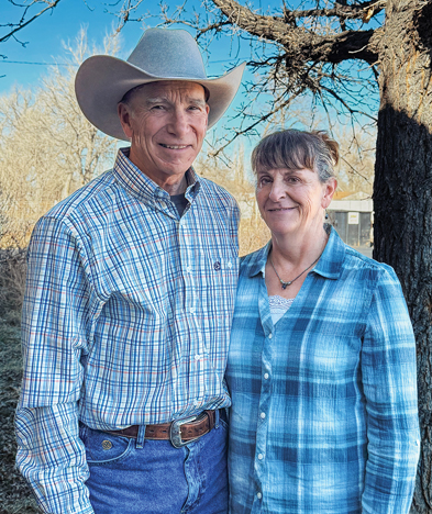 man wearing a cowboy hat and woman pose by a tree