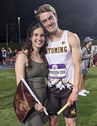 Two people holding UW flags at a track meet