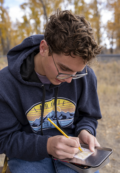 Student sits outside sketching in a notebook