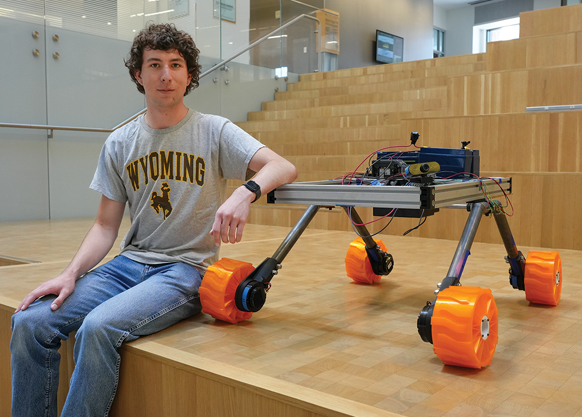 student sitting on steps with a robot