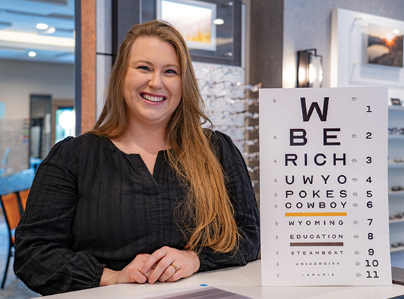 Person in an eye doctor's office standing next to an eye chart