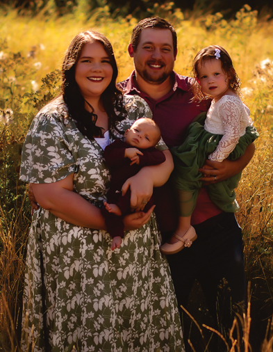 Family with young children pose outside in a field