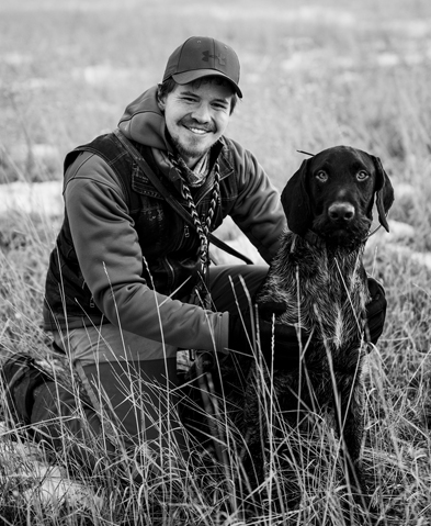 black and white image of a man and a dog in a field