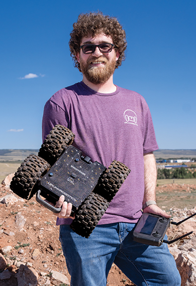 Person outside holding a remote control and robot with wheels