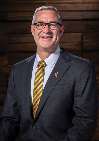 person in a suit in a studio portrait with a wood background