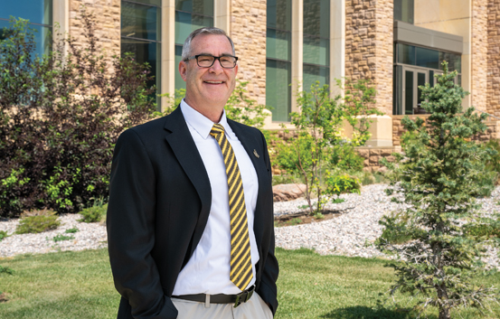 person in a black suit and gold tie standing outside the Gateway Center