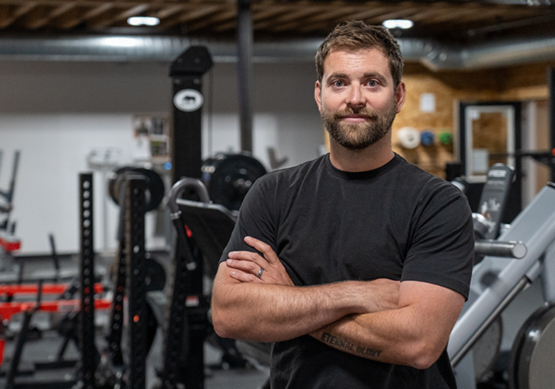 person with arms crossed in a gym