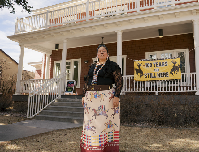 Female standing in front of a red house