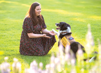 woman with a black and white dog wearing a service vest