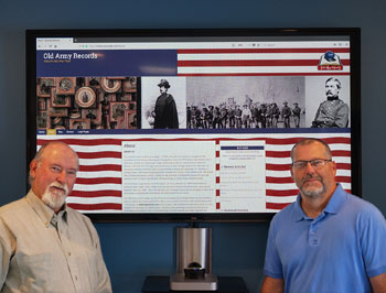two men standing in front of a video display