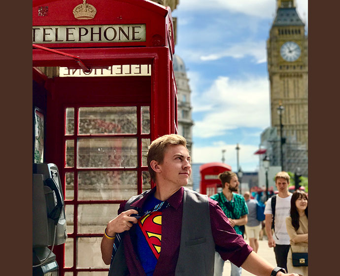 man with superman t-shirt standing by phone booth