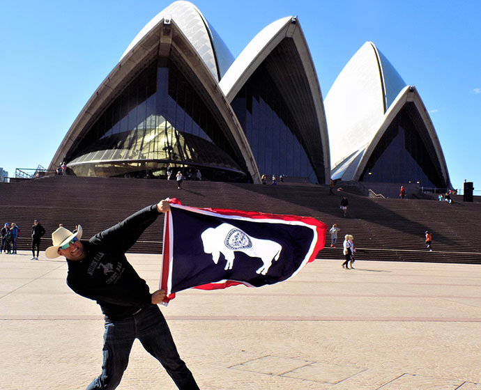 man holding Wyoming flag in front of the Sydney opera house