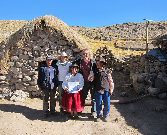 people standing in front of rustic stone thatched hut