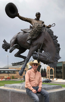 man sitting in front of bucking horse statue