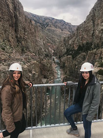 two women in hard hats at a railing overlooking a river gorge