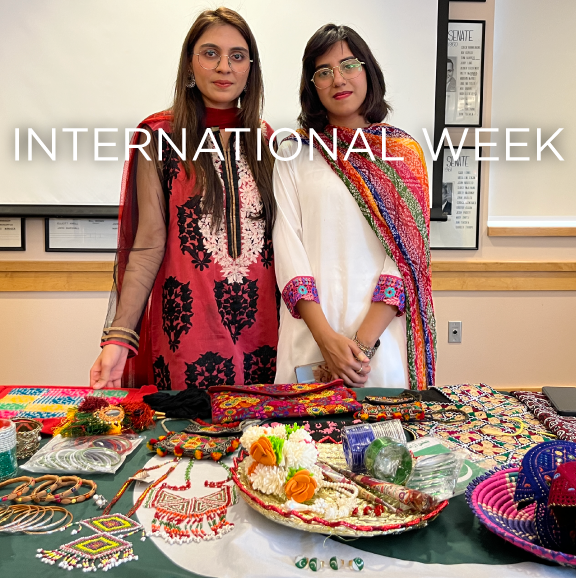 two women in traditional clothing of other cultures in behind a table full of hand-crafted items
