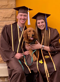 man and woman in cap and gown, holding a dog