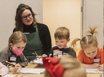 woman working with small children at a table creating art