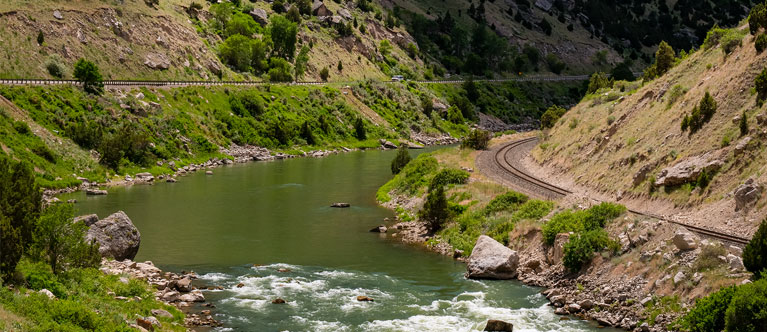 river and railroad tracks going through a canyon