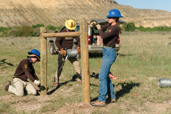 three people working on a fence