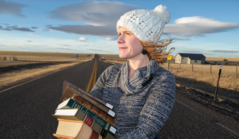 woman holding a stack of books by a highway