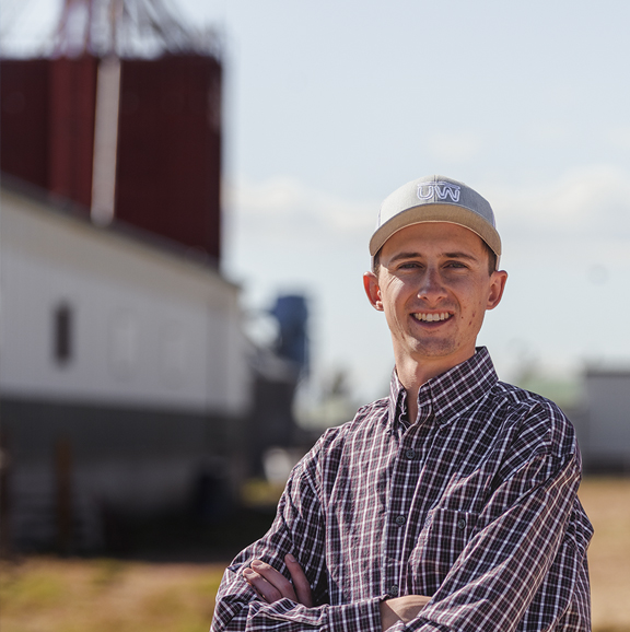 man outside with grain elevator in the background