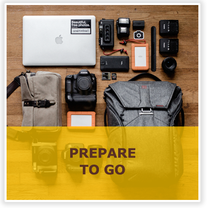 Prepare to go text with computer, backpack and items to take on a trip in background