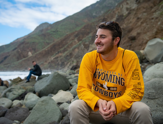 Student sitting on rocks seaside in New Zealand
