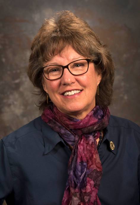 woman with brown hair, wearing glasses and a scarf