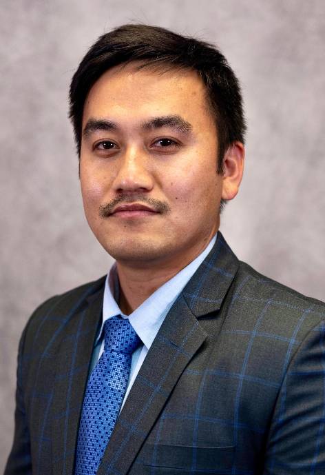 headshot of kiran gaha, man wearing grey plaid suit and blue tie