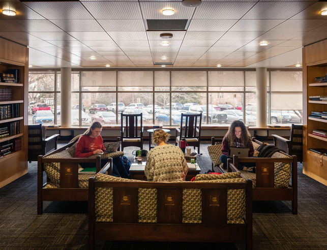 Three students work on computers in a comfortable seating area at UW's library