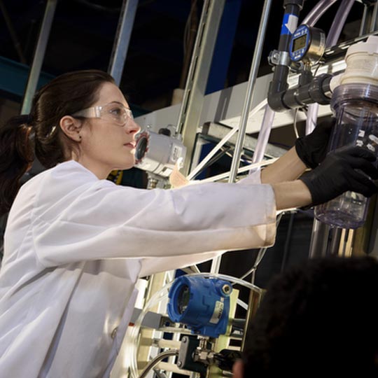Picture of a woman in a lab wearing safety goggles
