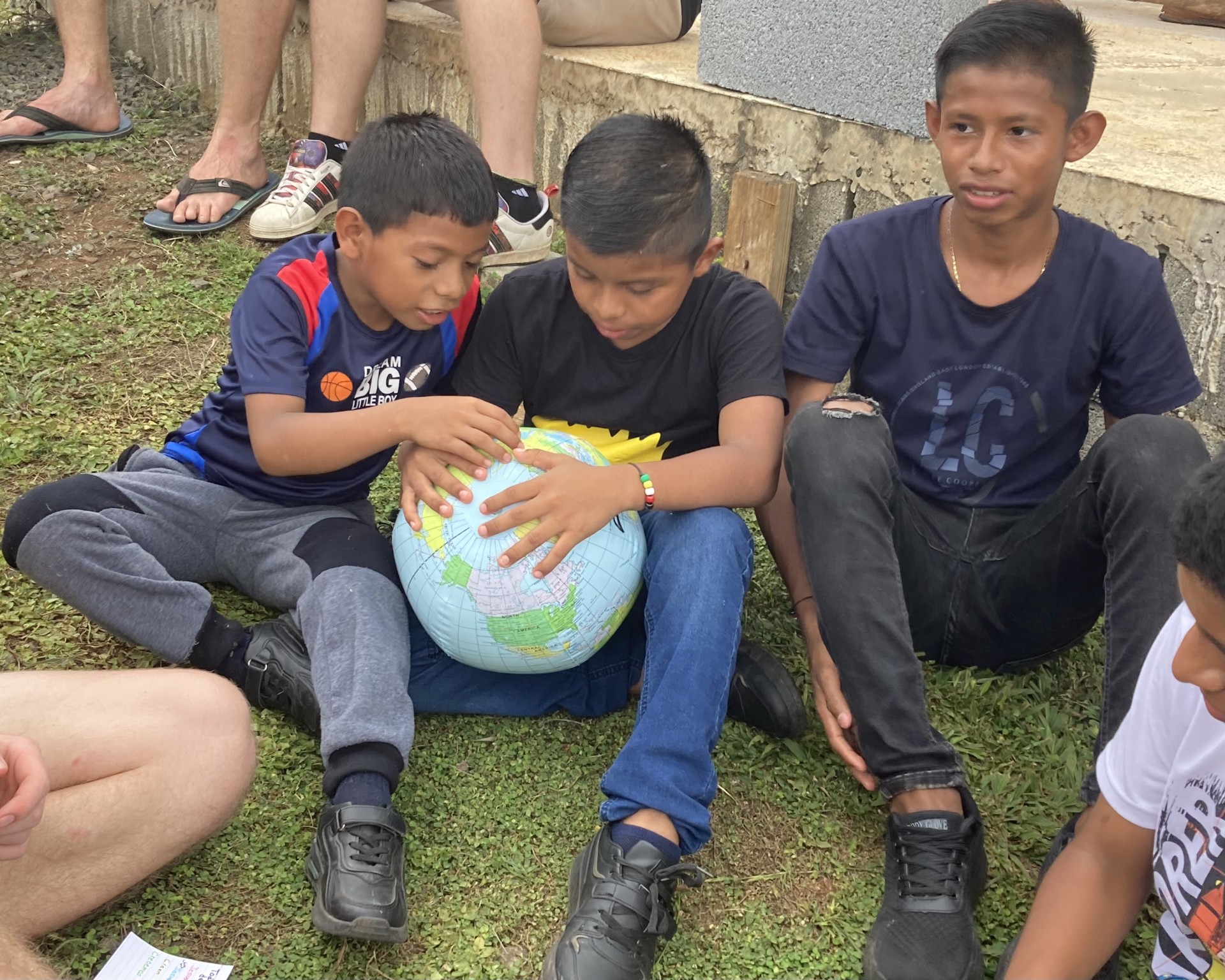 A group of children sitting on the ground and looking at a inflatable globe.