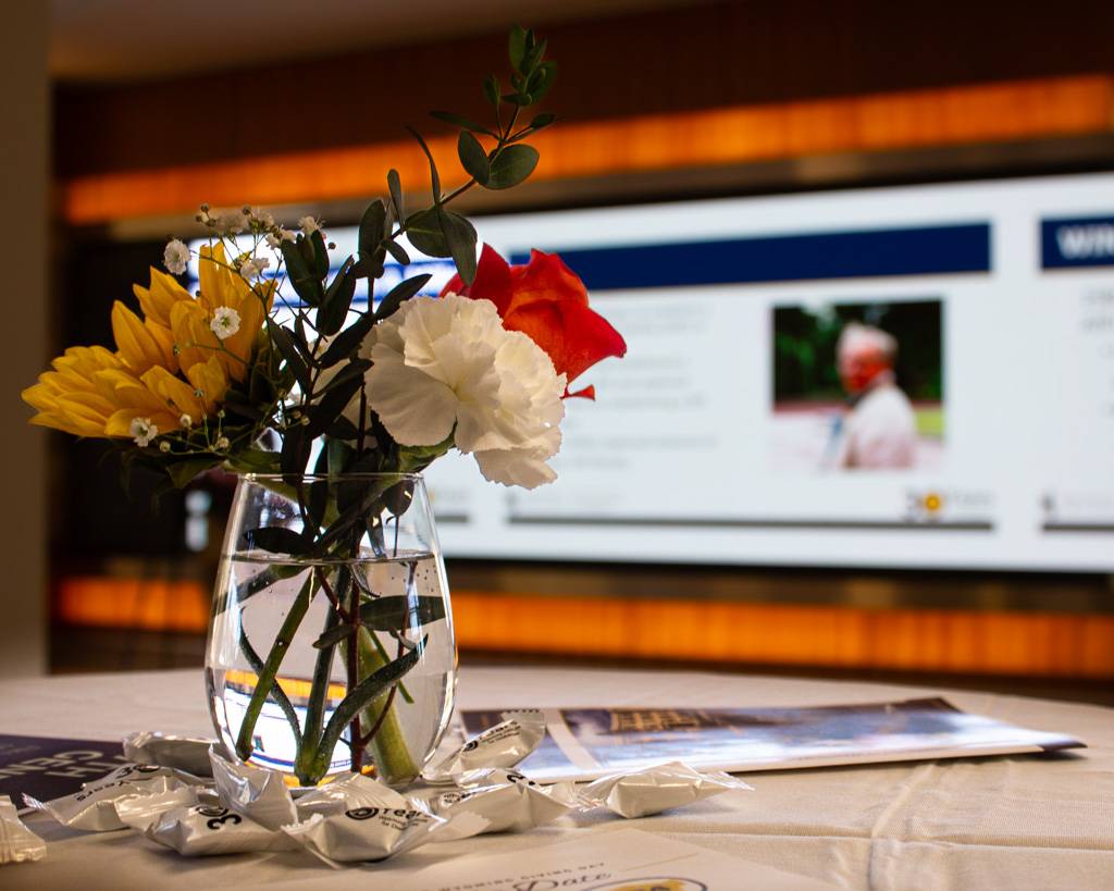 Colorful flowers in a vase on a table in front of the 30th-anniversary slideshow.