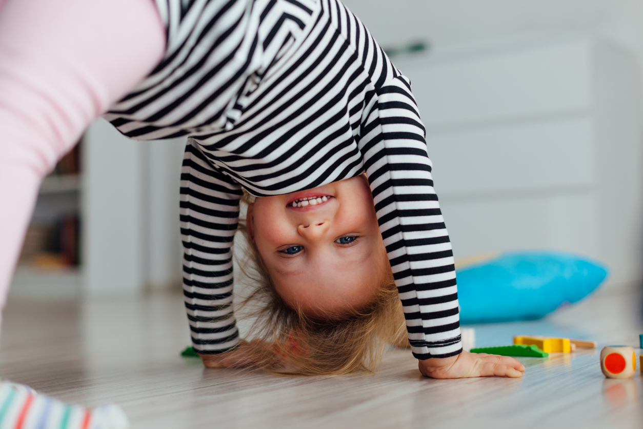 A smiling toddler looking upside down at the viewer