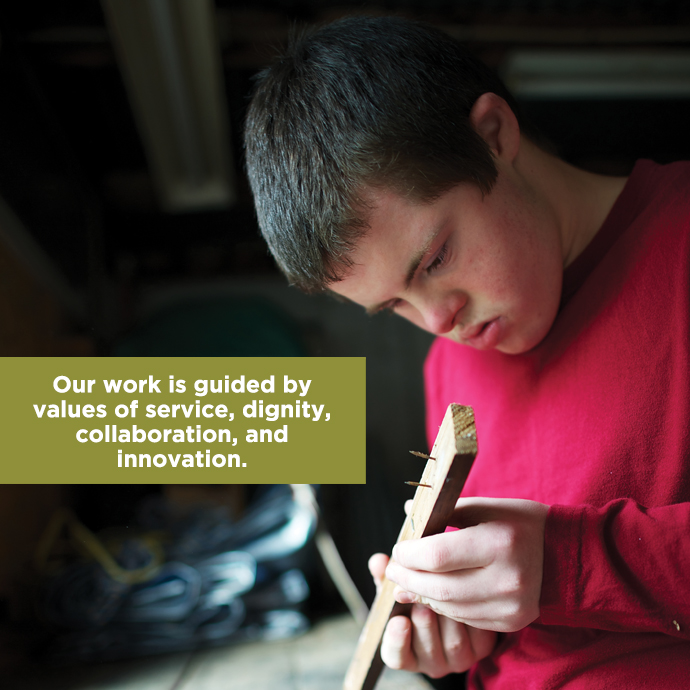 Young person with Down Syndrome working with a wood project, with text:Our work is guided by values of service, dignity, ollaboration and innovation.